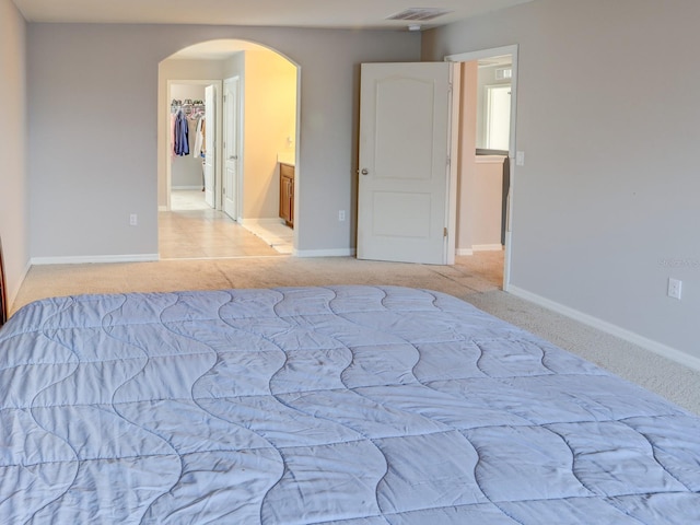 carpeted bedroom with ensuite bathroom, a walk in closet, and a closet