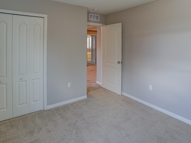 unfurnished bedroom with light colored carpet and a closet