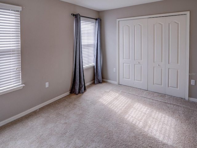 unfurnished bedroom featuring a closet and light colored carpet