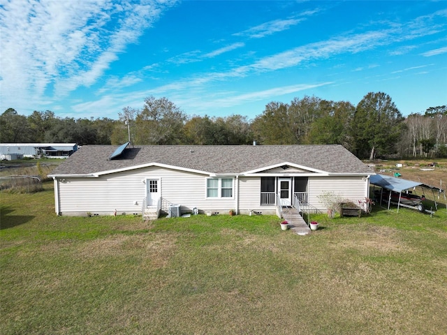 rear view of house with a carport, a yard, a sunroom, and central air condition unit