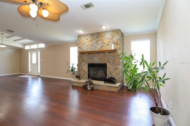 unfurnished living room with ceiling fan, ornamental molding, a healthy amount of sunlight, and a stone fireplace