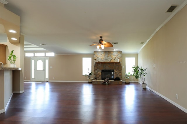 unfurnished living room with ceiling fan, ornamental molding, dark wood-type flooring, and a fireplace