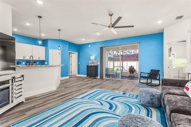 living room with hardwood / wood-style flooring, sink, and ceiling fan