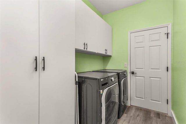 laundry area featuring hardwood / wood-style floors, washer and clothes dryer, and cabinets