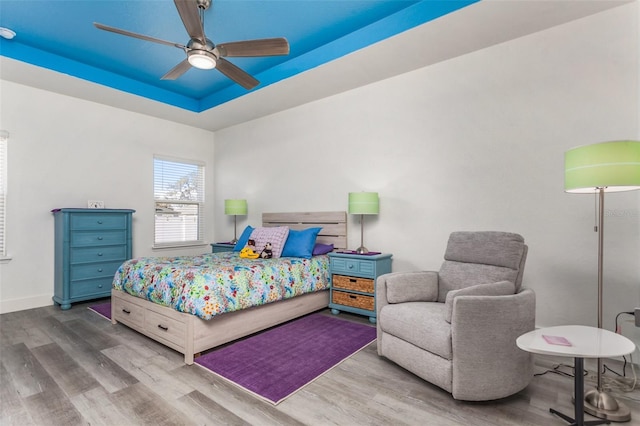 bedroom featuring hardwood / wood-style flooring, a raised ceiling, and ceiling fan