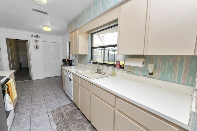 kitchen featuring cream cabinetry, light tile patterned flooring, white appliances, and sink