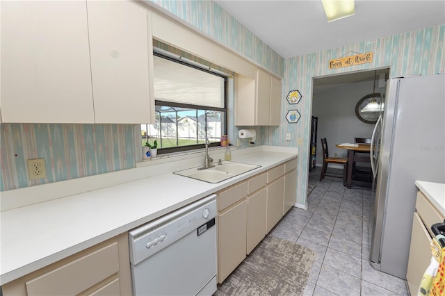 kitchen featuring light tile patterned flooring, white appliances, sink, and cream cabinets