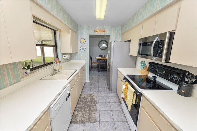 kitchen featuring sink, light tile patterned floors, stainless steel appliances, and cream cabinets