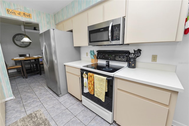 kitchen featuring cream cabinets, stainless steel appliances, decorative light fixtures, and light tile patterned flooring