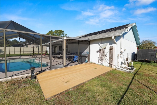 back of property with a lanai, a patio area, a lawn, and a fenced in pool