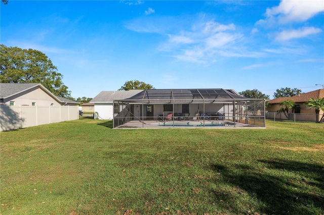 rear view of property featuring a lawn, glass enclosure, and a fenced in pool