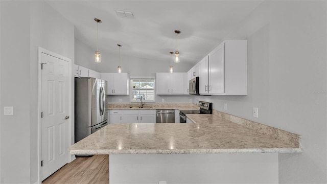 kitchen with kitchen peninsula, stainless steel appliances, vaulted ceiling, and white cabinets