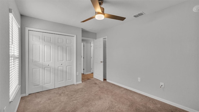 unfurnished bedroom featuring a closet, light colored carpet, and ceiling fan