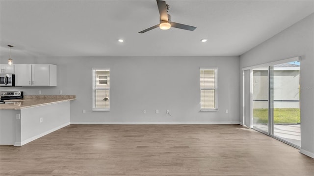 kitchen with white cabinets, hanging light fixtures, light wood-type flooring, appliances with stainless steel finishes, and kitchen peninsula