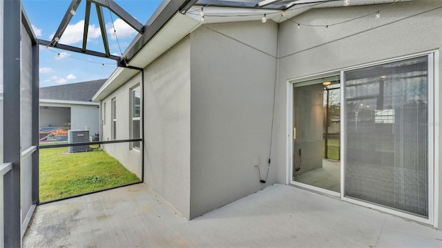 exterior space with a lawn, glass enclosure, cooling unit, and a patio