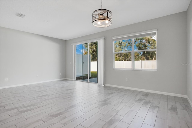 unfurnished room with a notable chandelier, a healthy amount of sunlight, and light hardwood / wood-style flooring