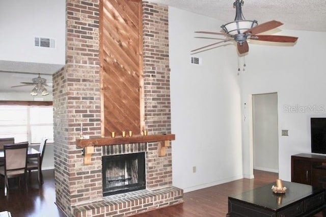 living room featuring ceiling fan, dark hardwood / wood-style floors, a textured ceiling, and a brick fireplace