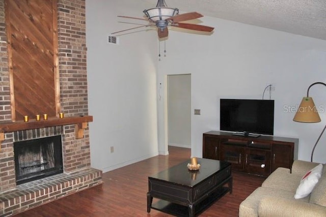 living room featuring lofted ceiling, ceiling fan, dark hardwood / wood-style floors, a textured ceiling, and a fireplace