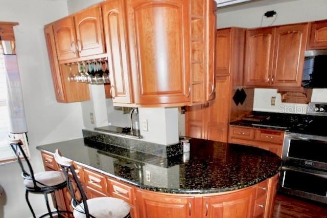 kitchen with stainless steel range with electric stovetop and dark stone counters