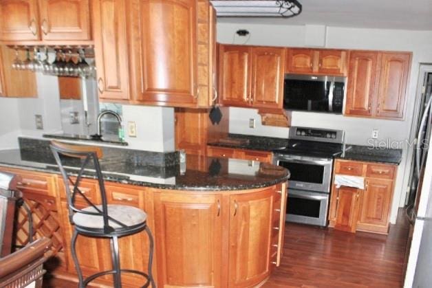 kitchen featuring electric range, sink, dark stone countertops, and dark wood-type flooring