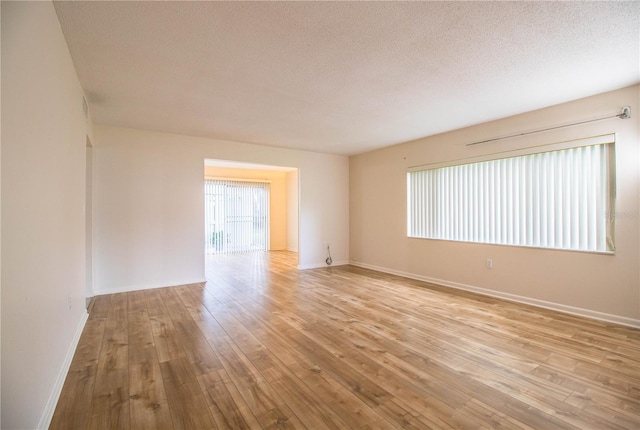 empty room with a textured ceiling and light hardwood / wood-style floors