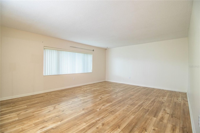 spare room with a textured ceiling and light wood-type flooring