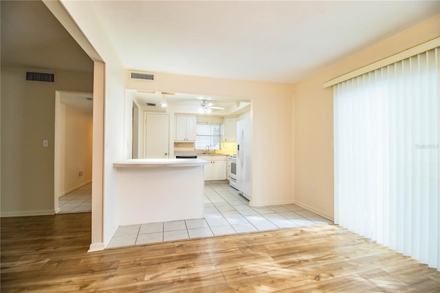 kitchen featuring sink, kitchen peninsula, ceiling fan, light wood-type flooring, and white cabinetry