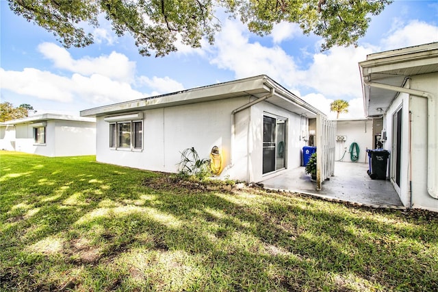 rear view of house featuring a lawn and a patio