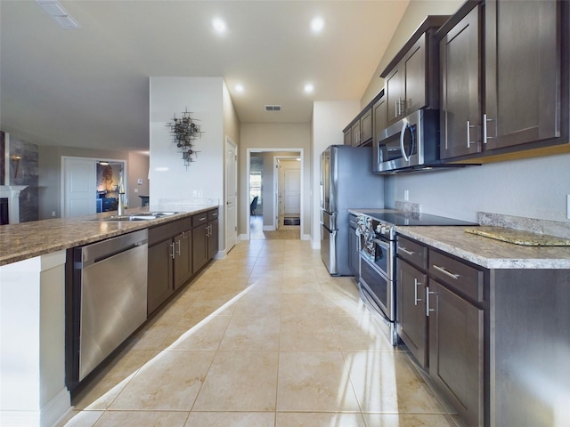 kitchen with dark brown cabinetry, appliances with stainless steel finishes, and light tile patterned floors