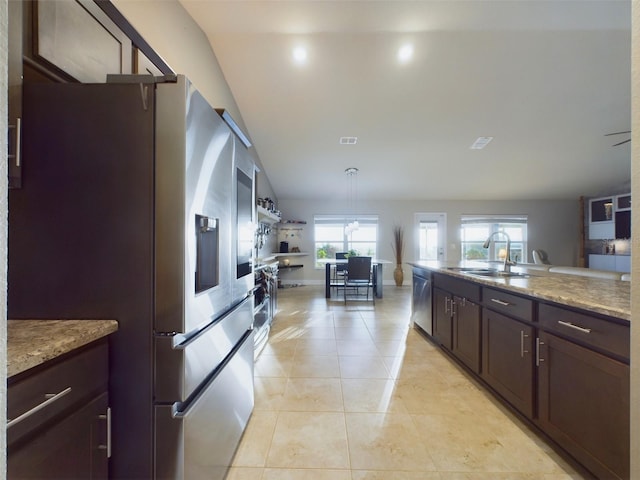 kitchen featuring appliances with stainless steel finishes, decorative light fixtures, sink, light tile patterned floors, and dark brown cabinets