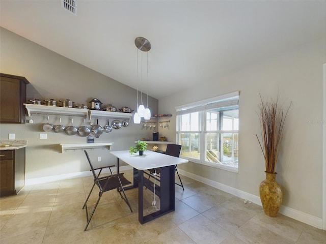 tiled dining room featuring vaulted ceiling