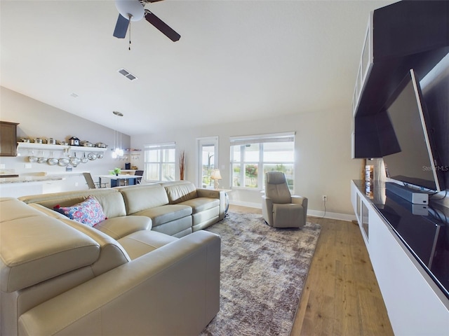 living room featuring ceiling fan, vaulted ceiling, and light wood-type flooring