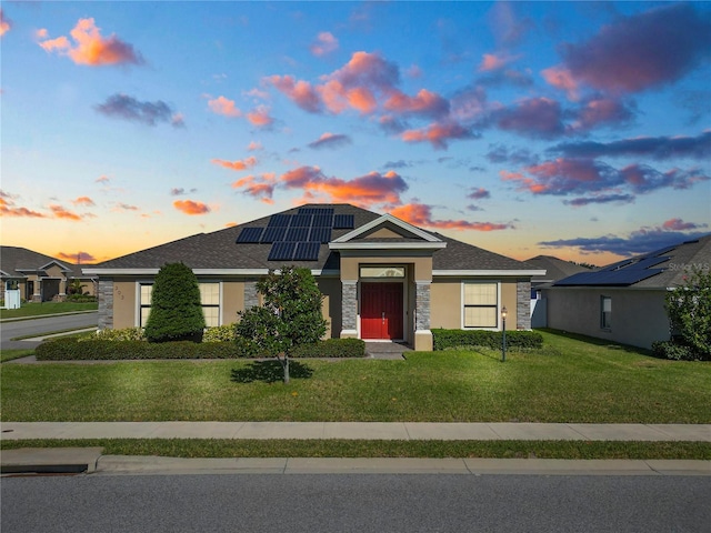 view of front of home with solar panels and a lawn