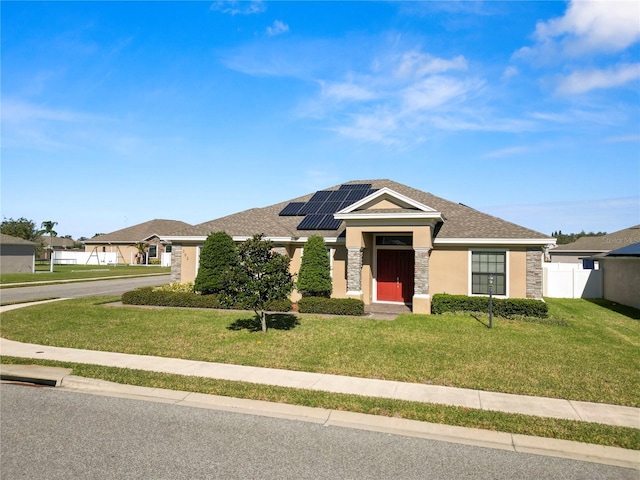 ranch-style home featuring a front yard and solar panels