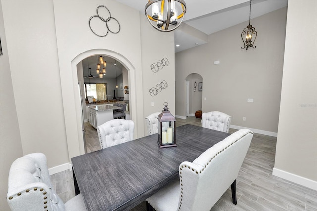 dining room with a towering ceiling, light wood-type flooring, and a notable chandelier