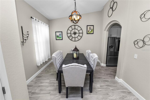 dining room with wood-type flooring, vaulted ceiling, and a notable chandelier