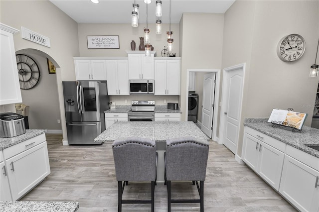 kitchen with decorative light fixtures, light stone countertops, white cabinetry, and stainless steel appliances