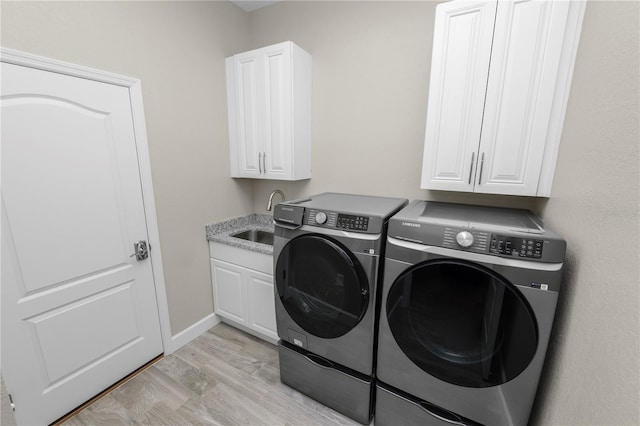 laundry area with separate washer and dryer, sink, cabinets, and light hardwood / wood-style flooring