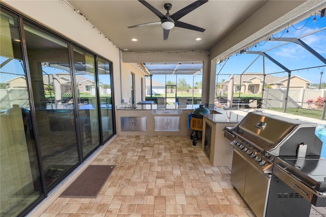 view of patio / terrace featuring ceiling fan, a grill, exterior kitchen, and glass enclosure