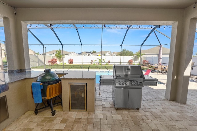 view of patio with area for grilling and glass enclosure