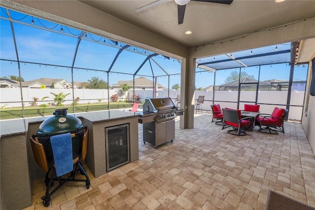 view of patio / terrace featuring ceiling fan, glass enclosure, area for grilling, and beverage cooler