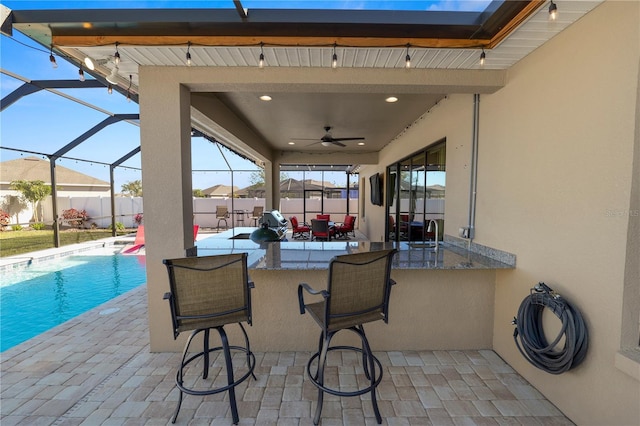 view of patio with ceiling fan, a fenced in pool, and a bar