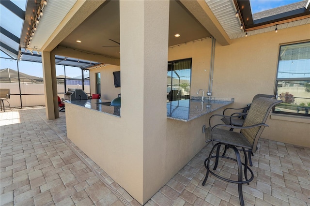 view of patio / terrace with a grill, a lanai, and a wet bar