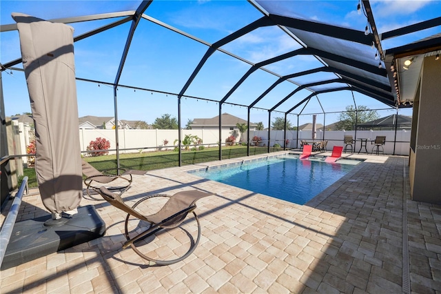 view of pool with a lawn, glass enclosure, and a patio area