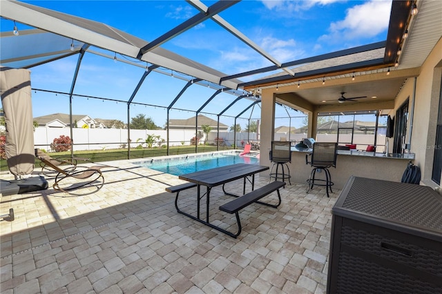 view of patio / terrace with a fenced in pool, glass enclosure, ceiling fan, and a bar