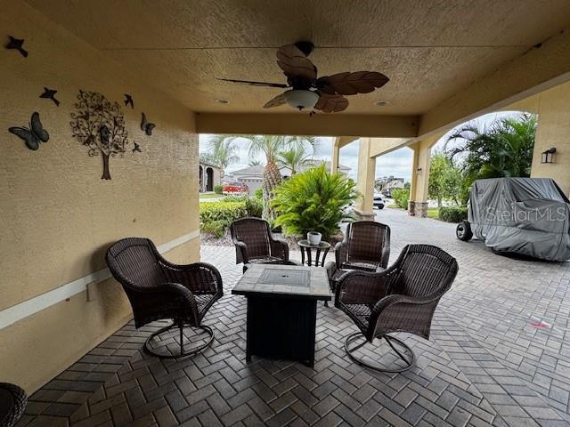 view of patio / terrace with ceiling fan and an outdoor living space with a fire pit