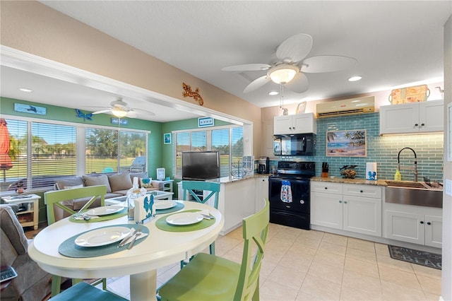 kitchen featuring black appliances, white cabinets, an AC wall unit, and sink