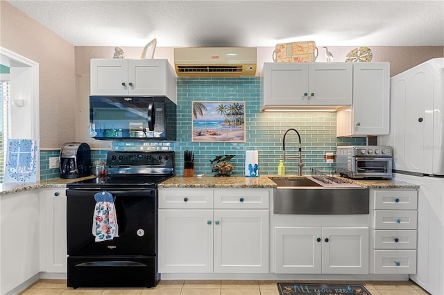 kitchen featuring light tile patterned floors, backsplash, white cabinetry, and black appliances