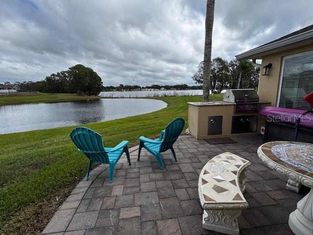 view of patio featuring a water view, area for grilling, and exterior kitchen