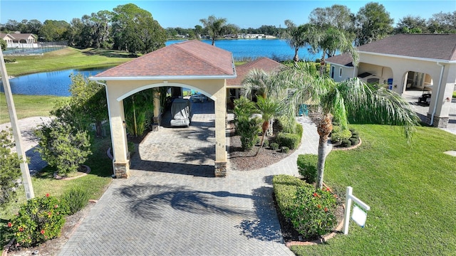 view of home's community with a yard, a carport, and a water view